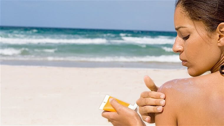 woman applying sunscreen at beach
