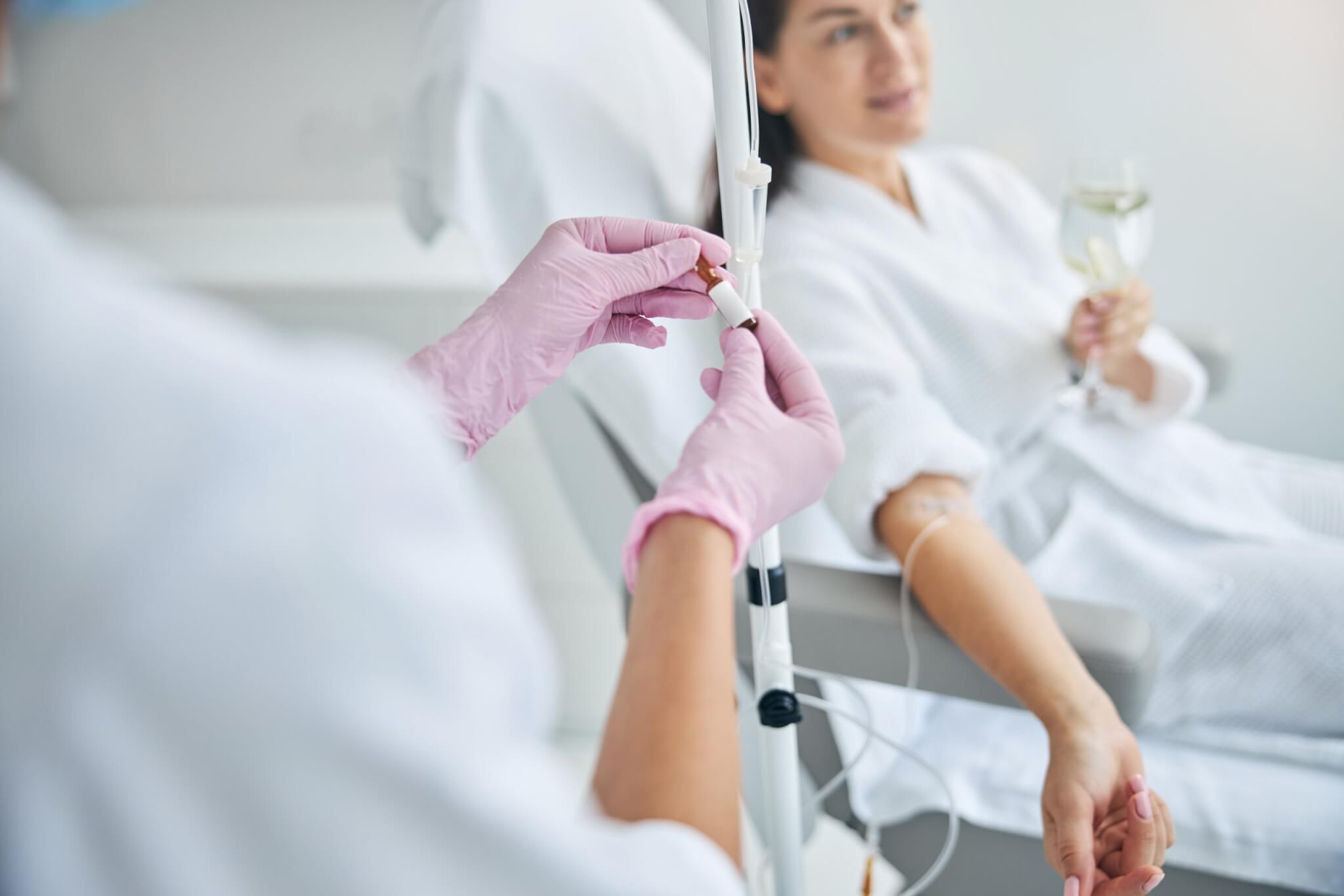 Spa client with a glass of drink in her hand looking away during the intravenous therapy