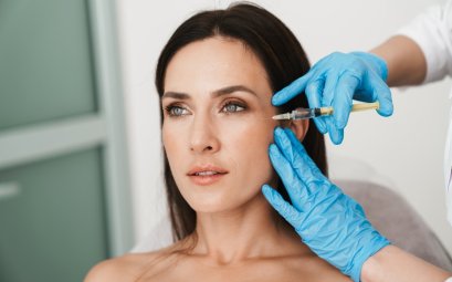 Photo of beautiful woman getting botox Dysport treatment in face by specialist in gloves in beauty salon